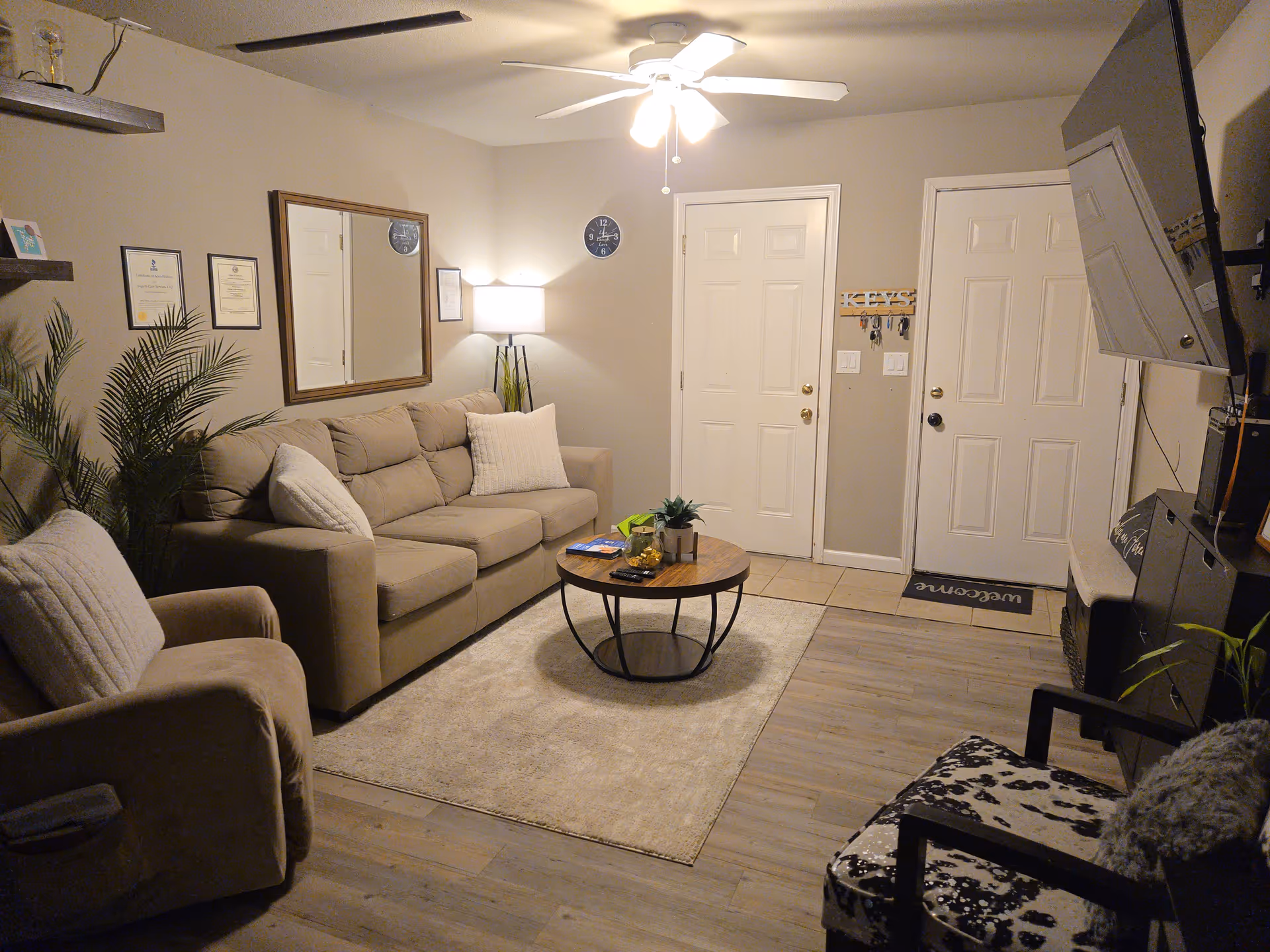 Cozy living room with beige couches, coffee table, and wall decor in a senior care facility.