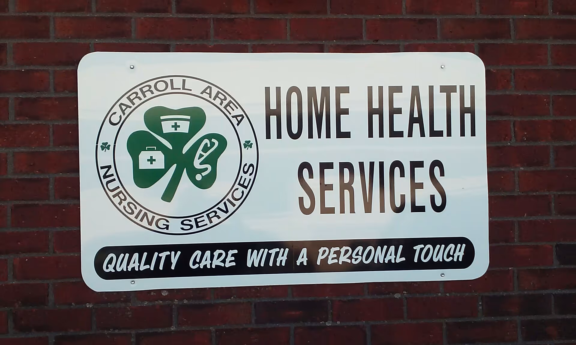 White rectangular sign on a brick wall reads Home Health Services with a nursing logo.