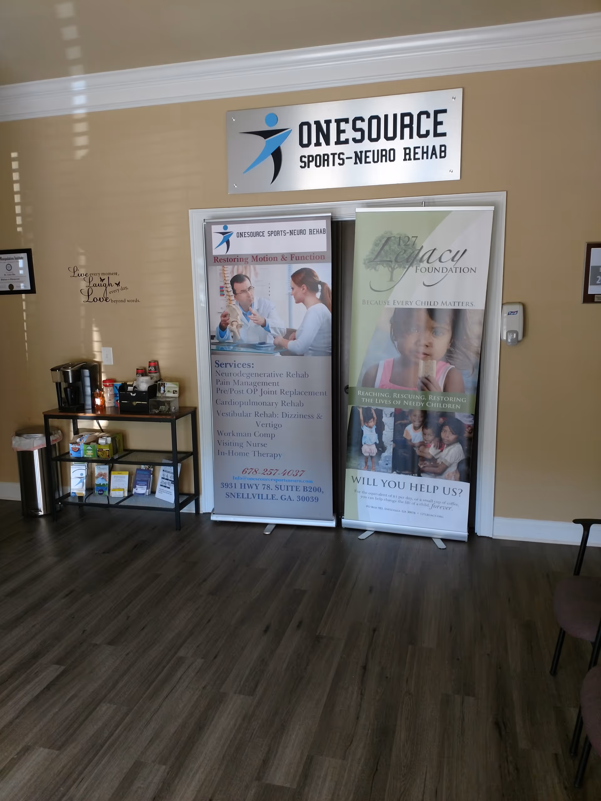 Lobby area featuring Onesource Sports-Neuro Rehab sign and promotional banners.