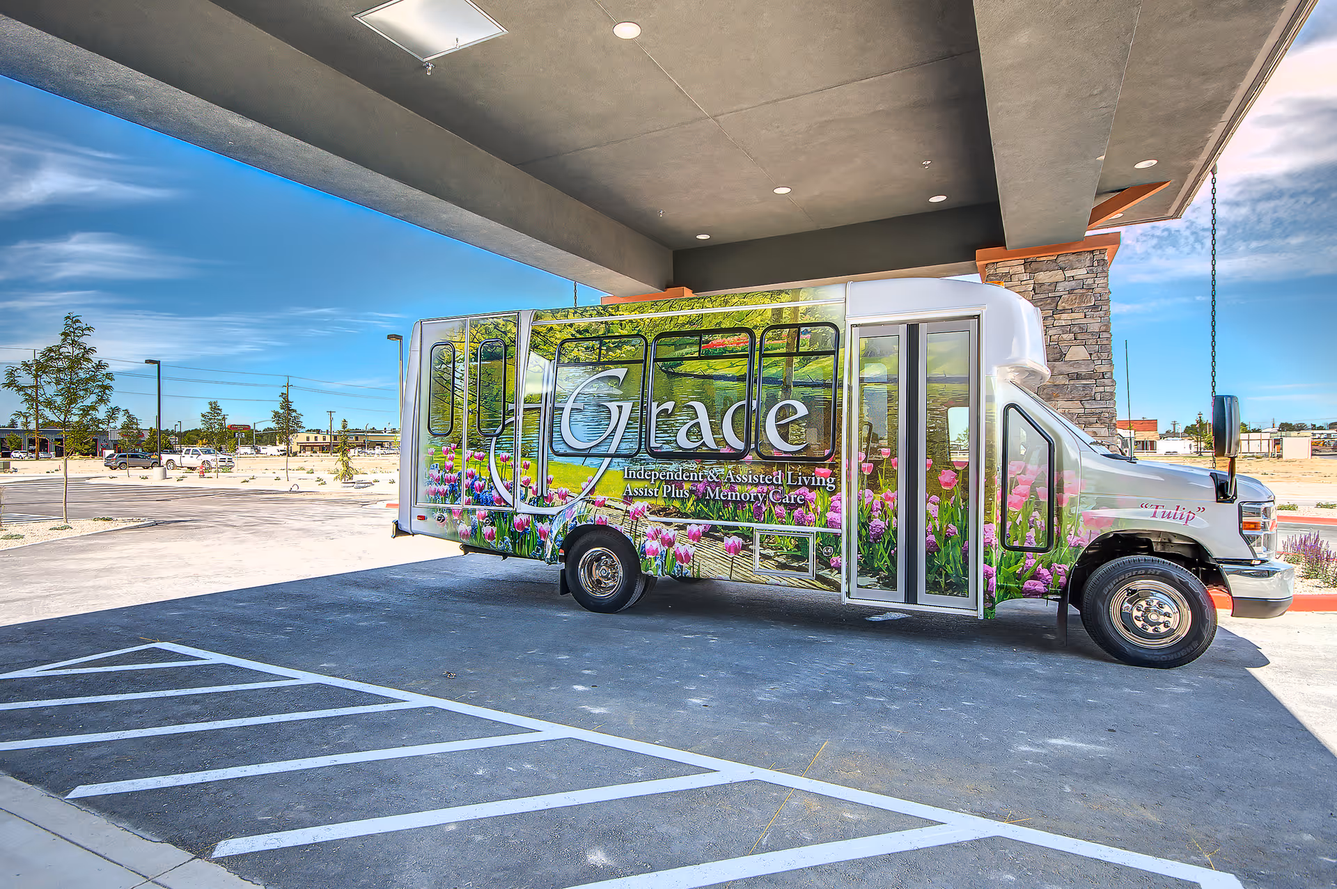 Colorful Grace bus with flower graphics parked at the covered entrance of Grace Assisted Living Caldwell.