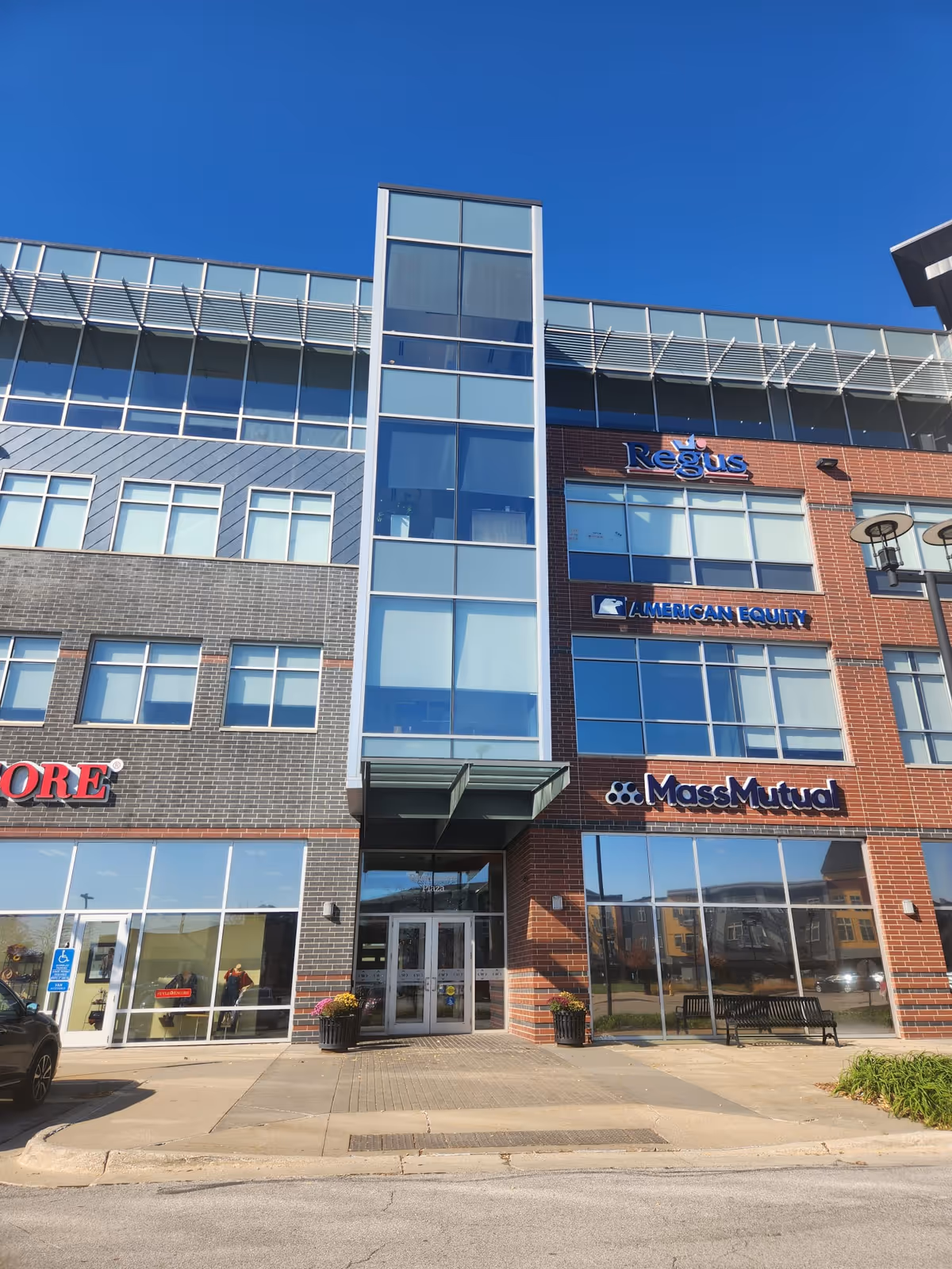 Modern multi-tenant office building with glass windows and brick facade under blue sky