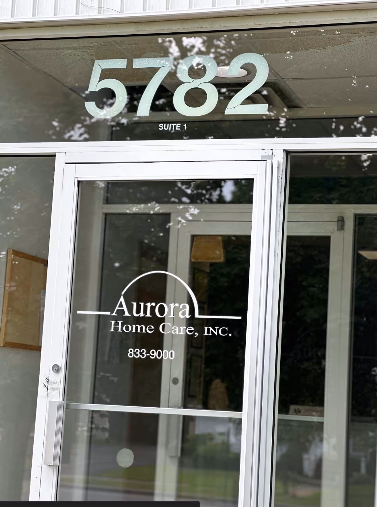 Glass entry door with Aurora Home Care, Inc. sign and suite number above.
