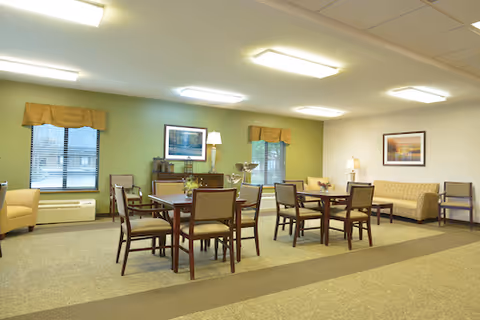 Spacious senior living common room with tables, chairs, sofas, and soft lighting