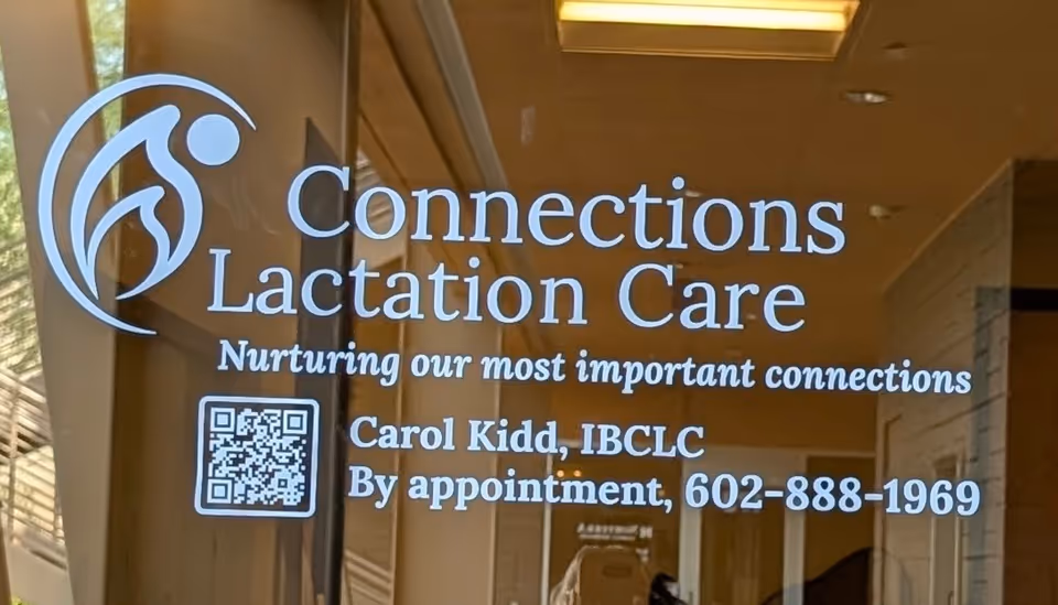 Glass storefront door displaying Connections Lactation Care sign and QR code.