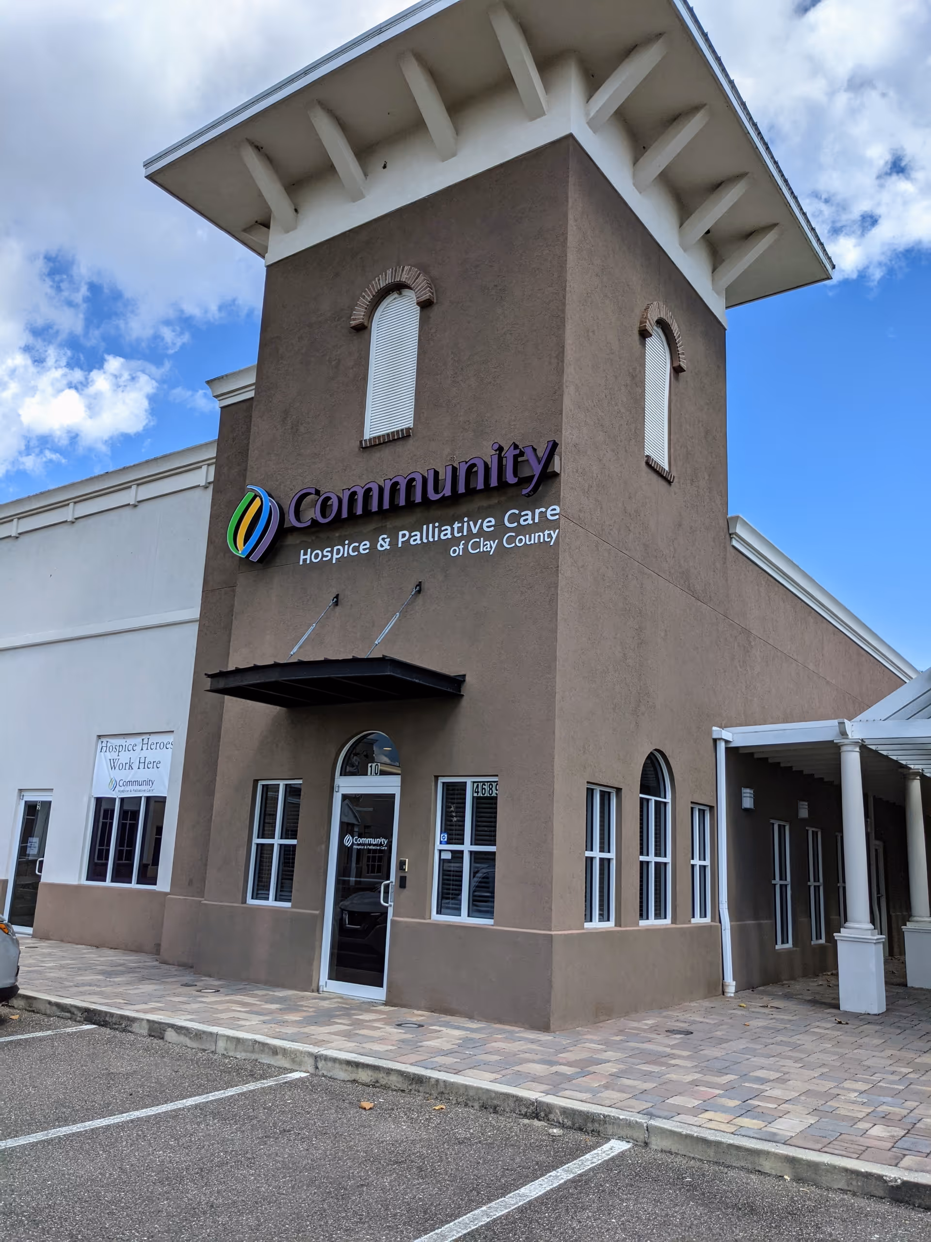Exterior view of a tan hospice building with Community sign and entrance.