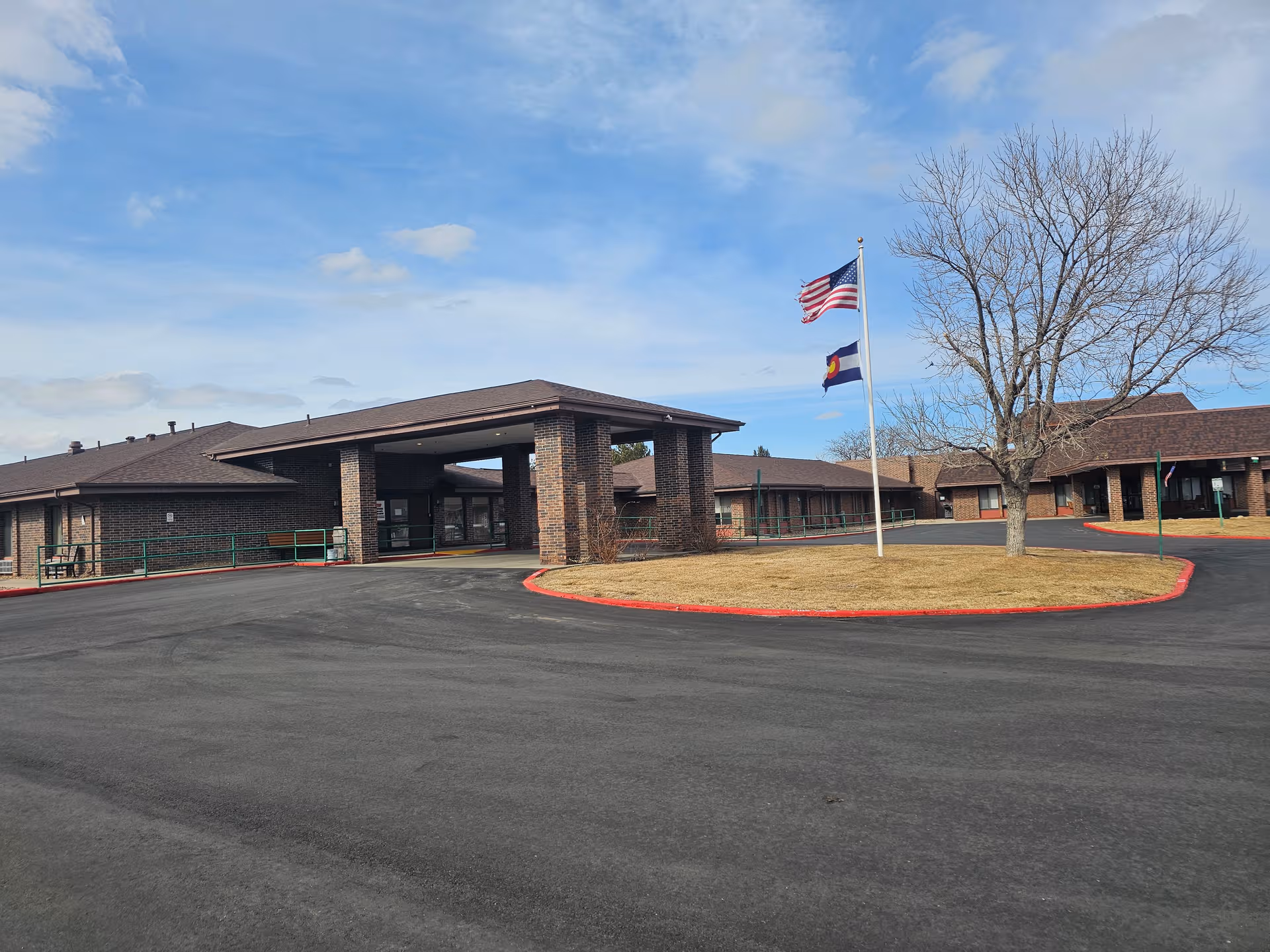 Exterior view of Skylake Post Acute facility with brick entrance, flags, and circular driveway.