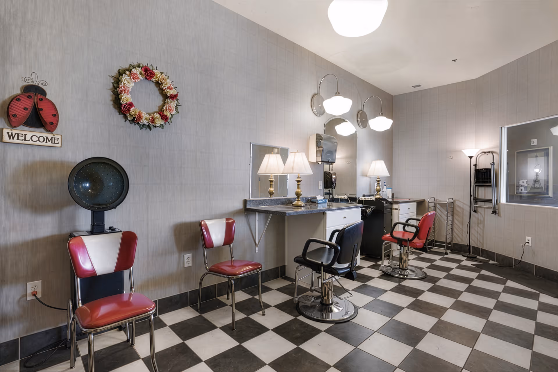 Senior living facility hair salon with red chairs, mirrors, and checkered floor.