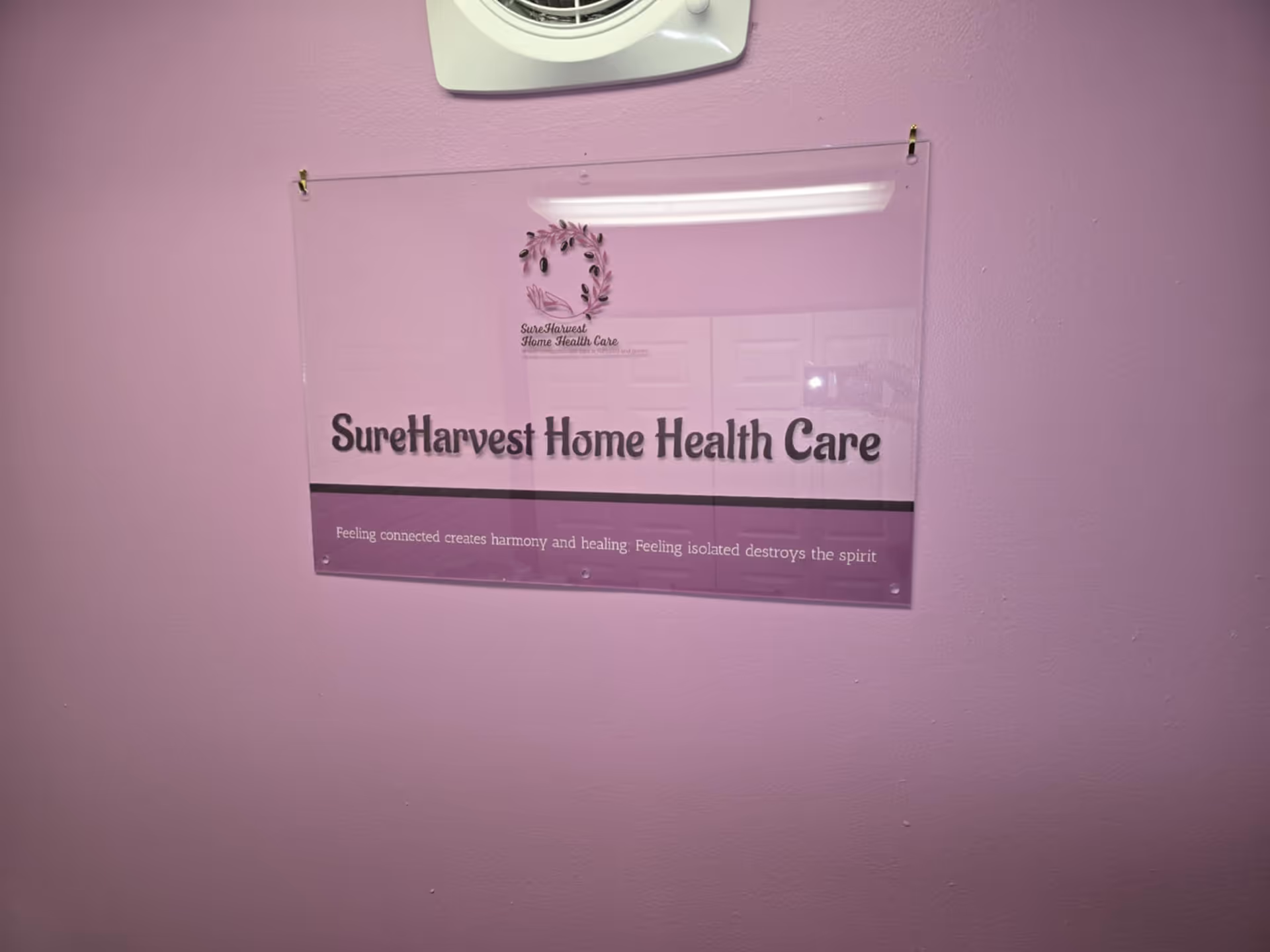 Interior pink-walled hallway with a mounted SureHarvest Home Health Care sign.