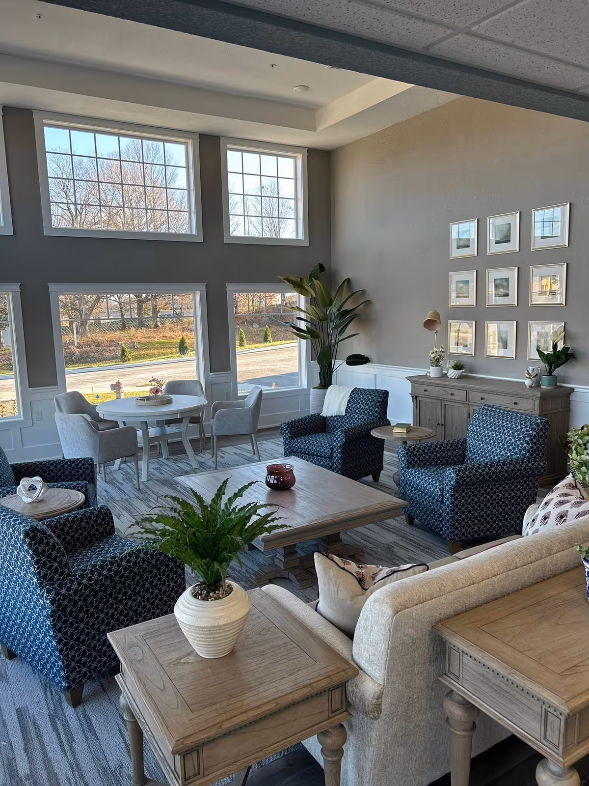 Bright living room with blue patterned chairs, neutral sofa, and large windows.