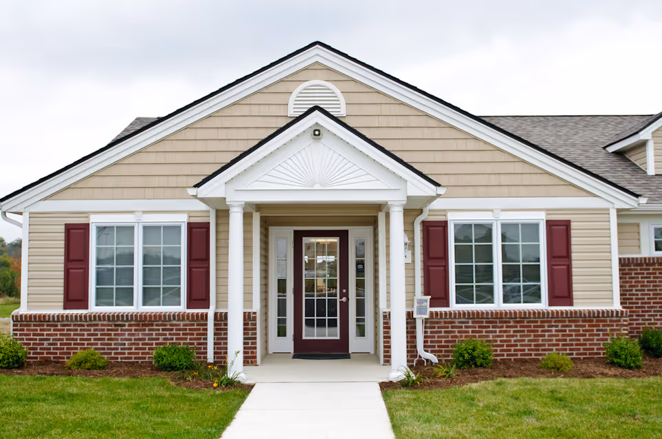 Front view of Whitehouse Square Senior facility with beige siding and brick base.
