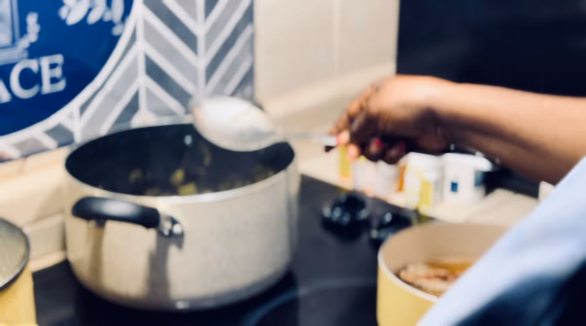 A caregiver stirs a pot on the stove in a kitchen at a care home