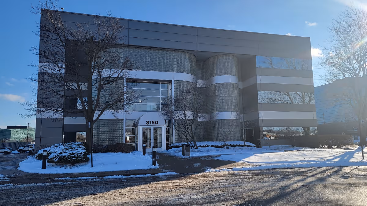 Modern facility building with a glass entrance and snow-covered landscaping.