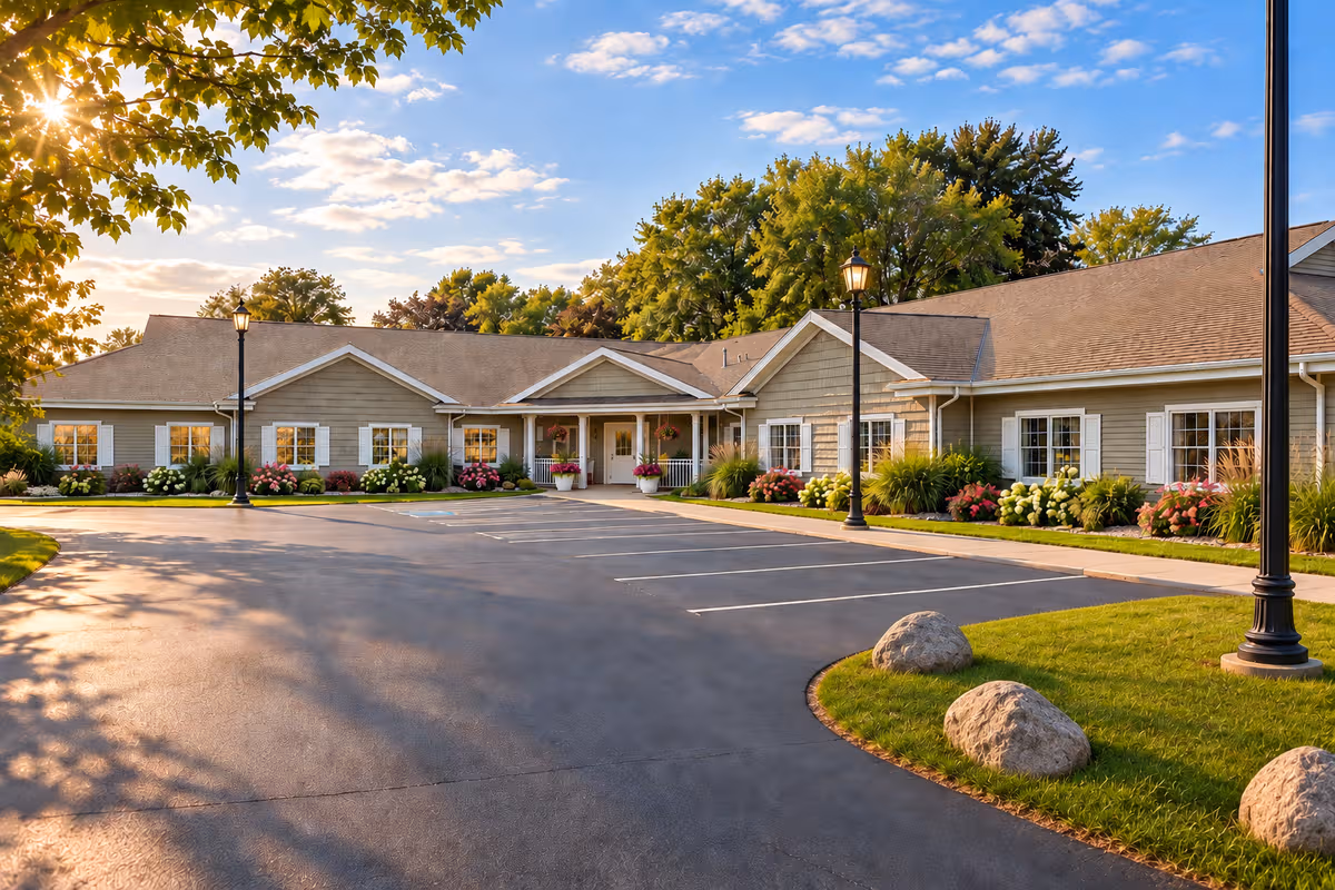 Exterior view of a senior living facility with a parking lot and landscaped entrance.