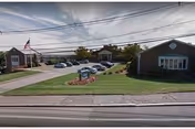 Exterior view of Golden Crest Nursing Centre with lawn, flag, and parked cars.