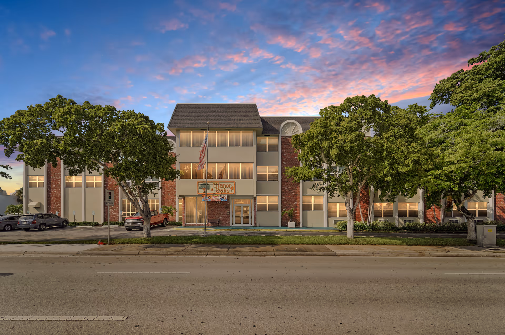 Exterior facade of The Savoy at Fort Lauderdale senior living, with trees along the street.