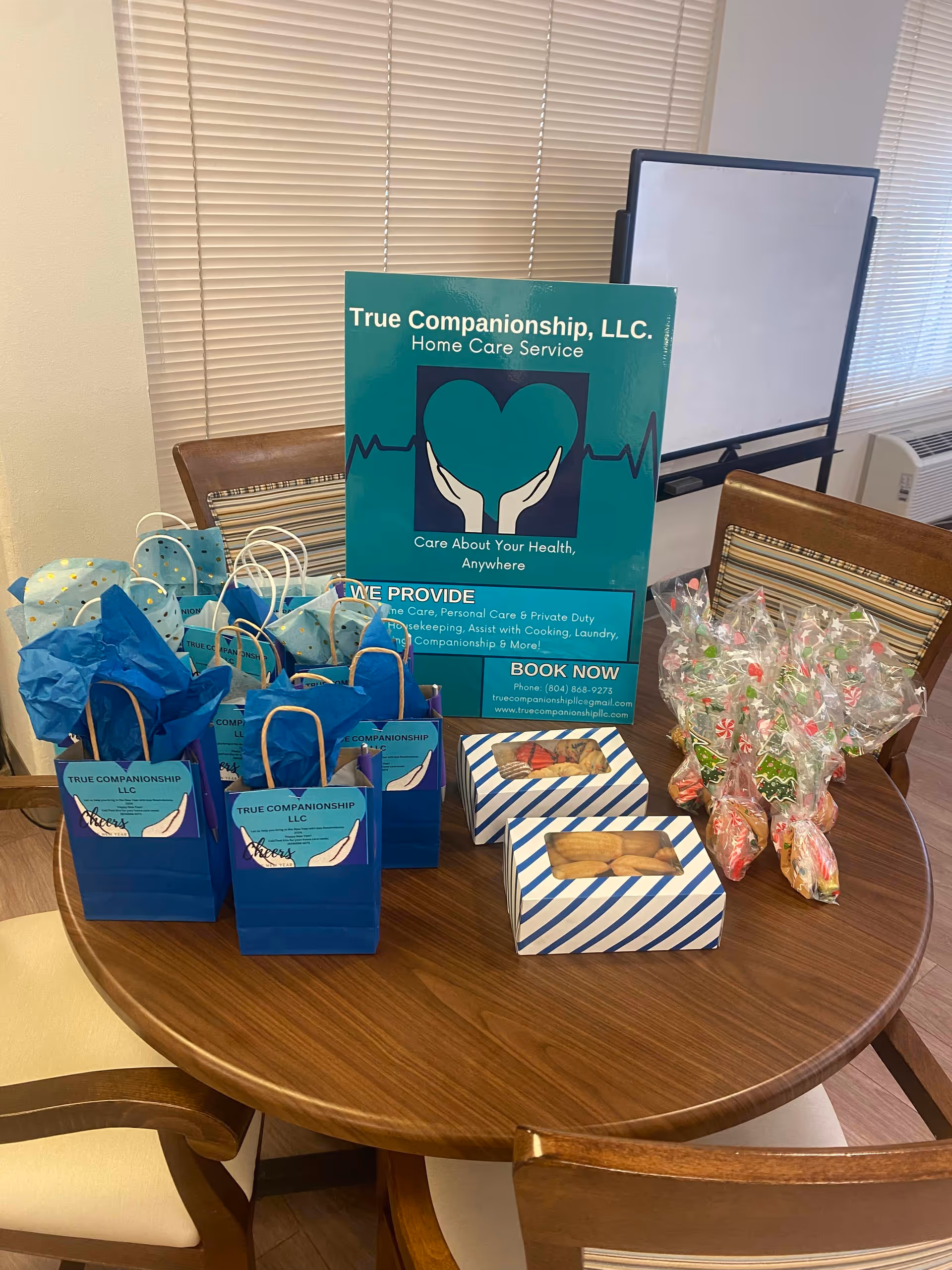 Round table with blue gift bags and a True Companionship LLC sign indoors