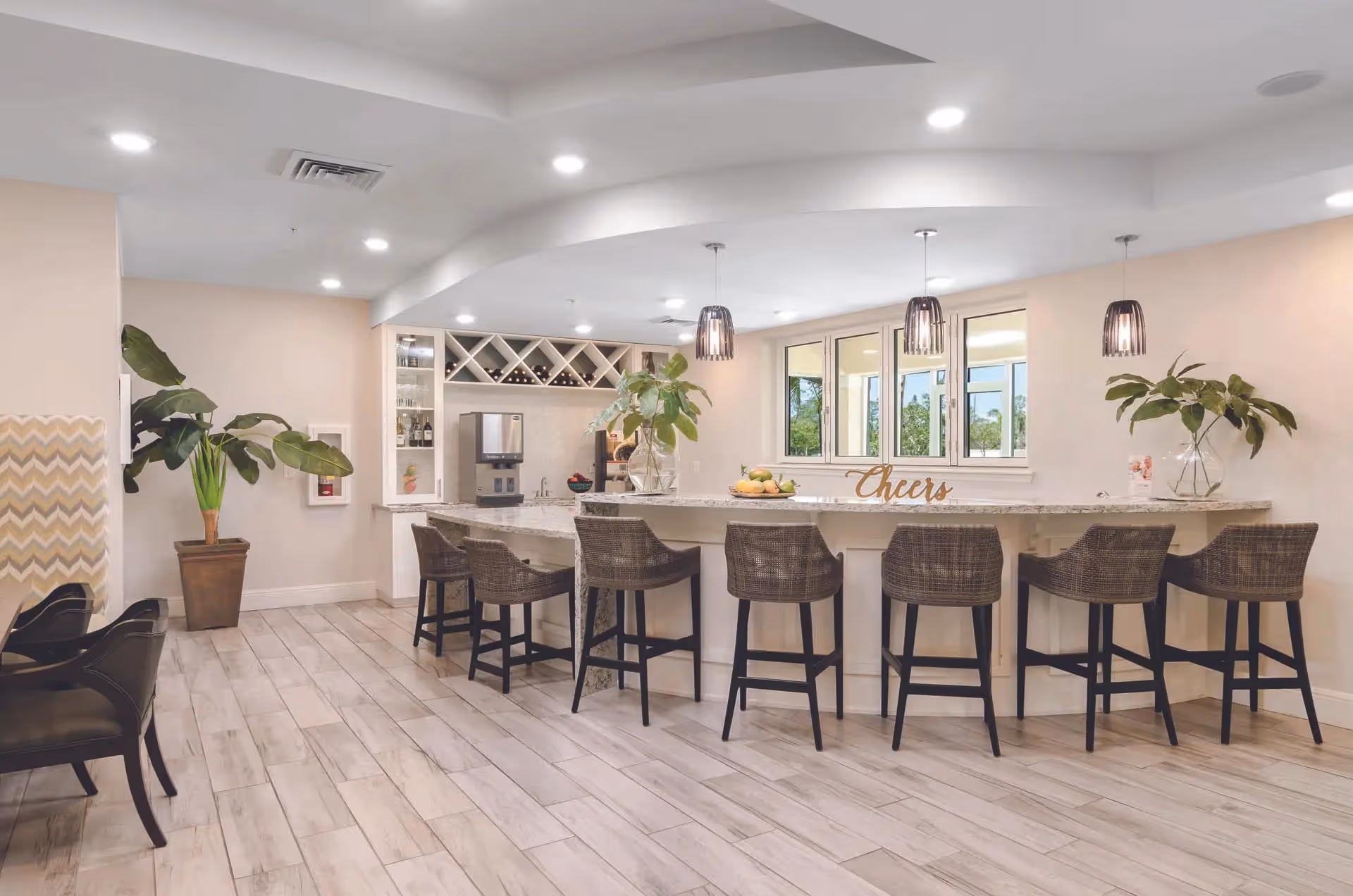 Bright modern dining area with a long marble counter, bar stools, pendant lights, and plants.