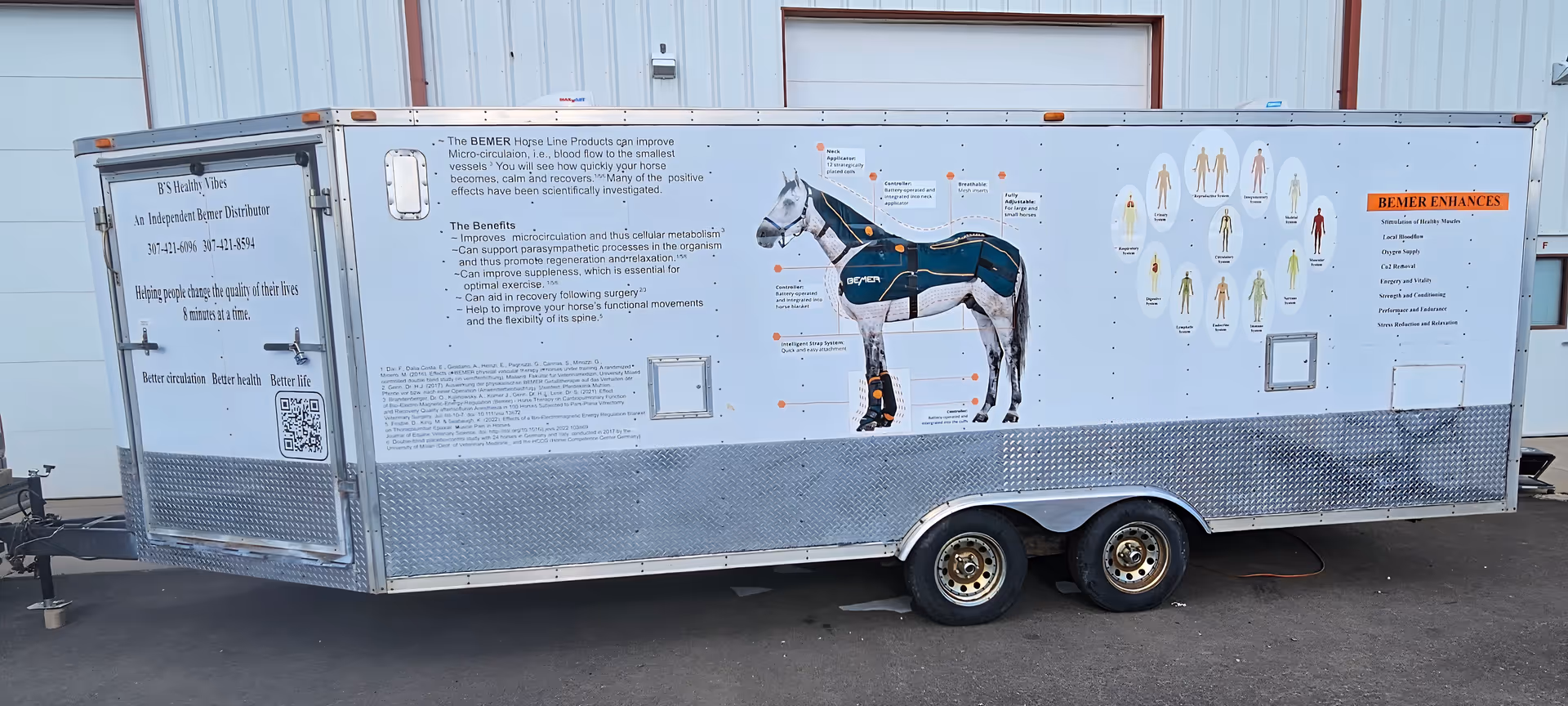 A long silver educational trailer labeled B's Healthy Vibes sits outside with diagrams.