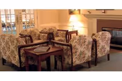 Floral upholstered seating around a coffee table with lamps and a fireplace in cozy living room.
