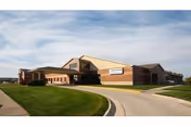 Exterior view of Schowalter Villa senior living facility with brick front, curved driveway, and green lawn.
