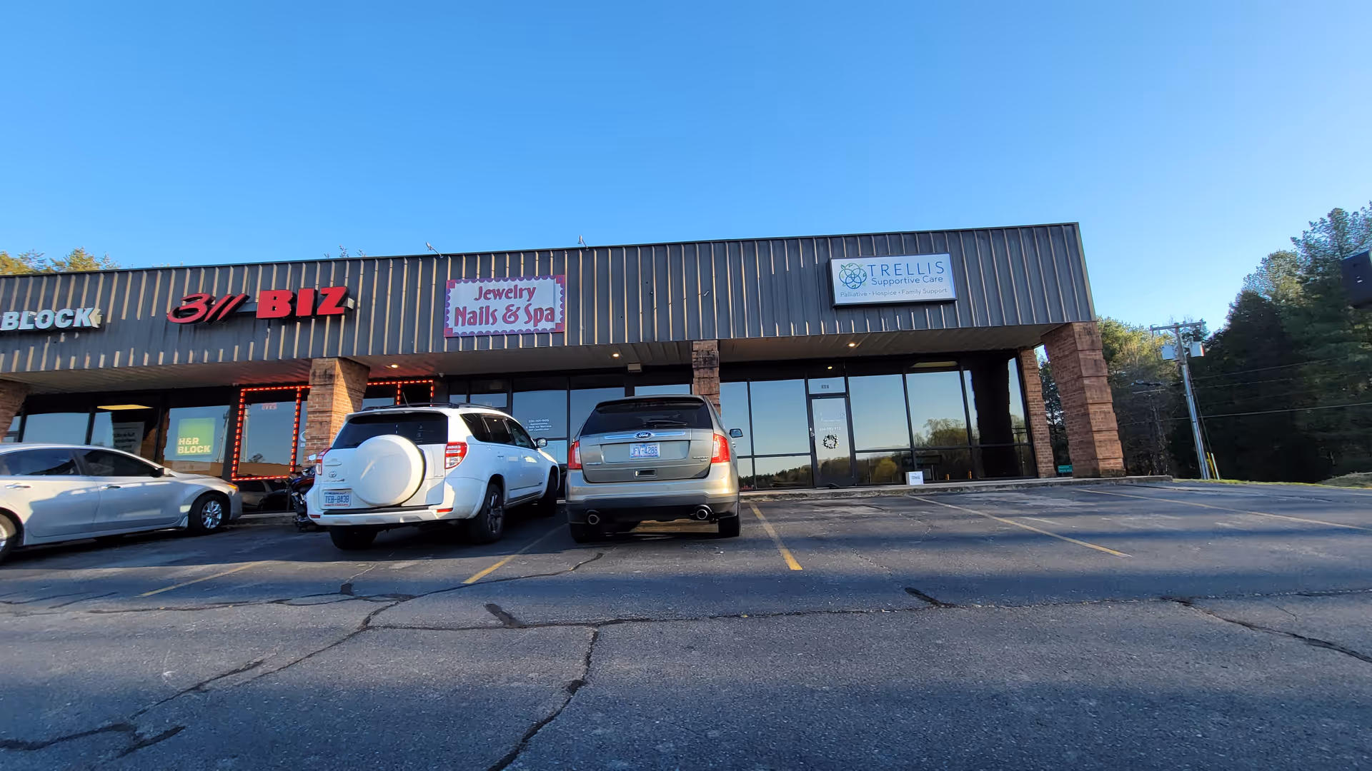 Front exterior of a strip mall with Trellis Supportive Care Stokes signage and parked cars.