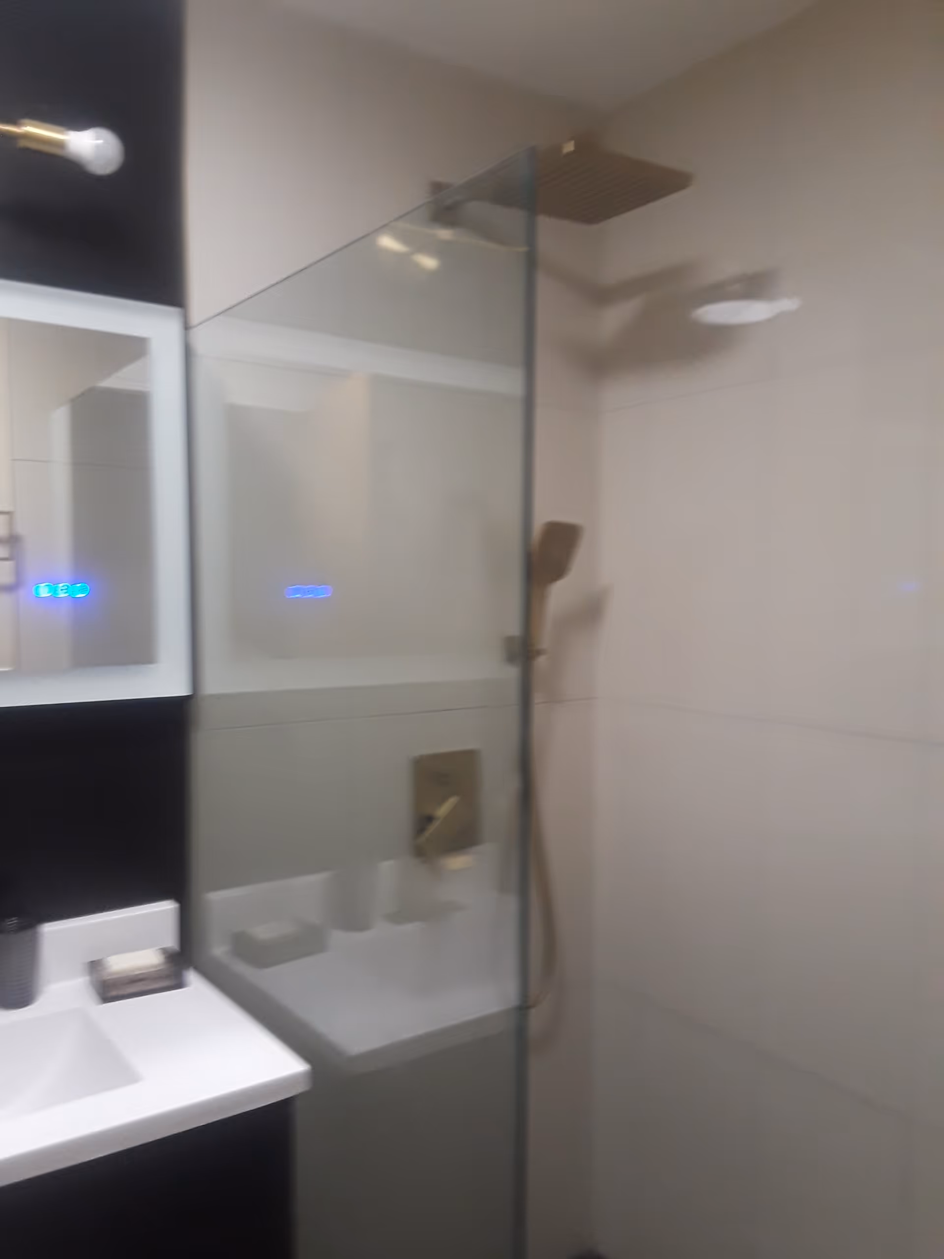 Modern bathroom with glass shower enclosure, sink, and mirror cabinet.