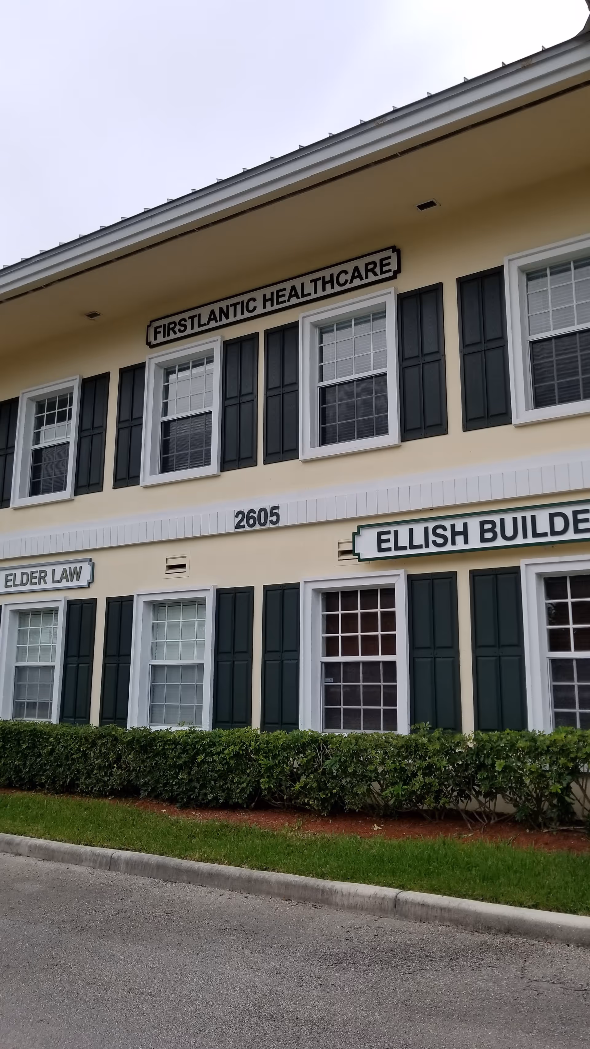 Two-story beige building with dark shutters and FirstLantic Healthcare signs.