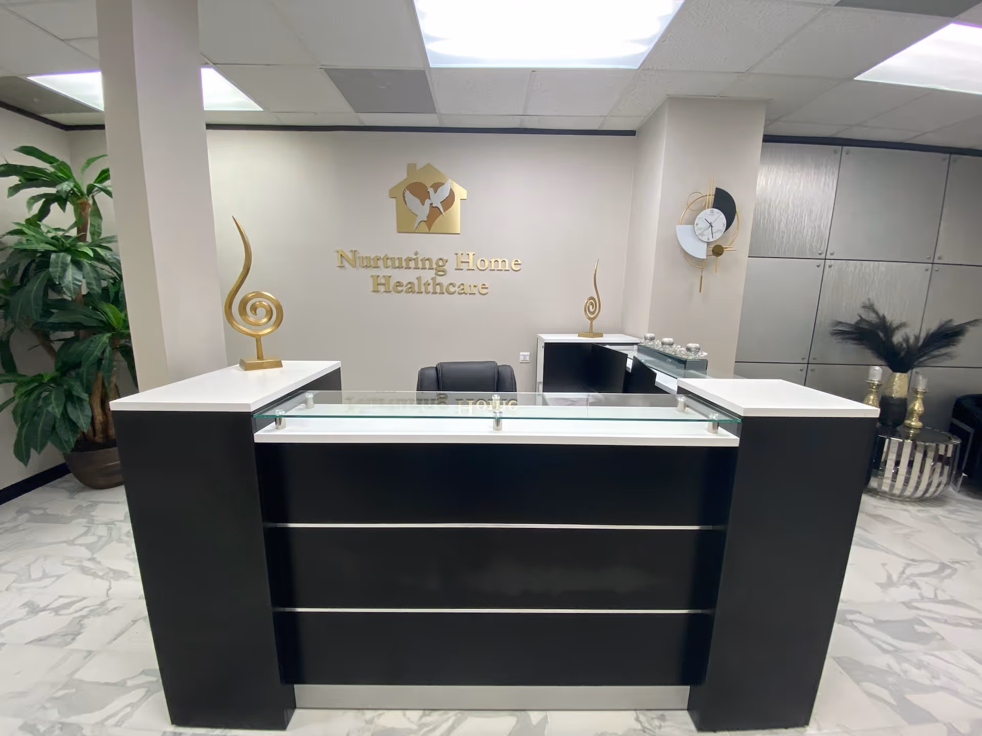 Reception desk in a modern lobby with Nurturing Home Healthcare signage on wall.