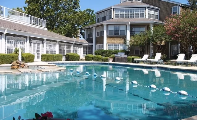 Outdoor swimming pool with lounge chairs in front of a multi-story residential building at Independence Village.