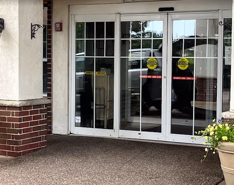 Glass double doors of the building entrance with caution stickers and a potted plant