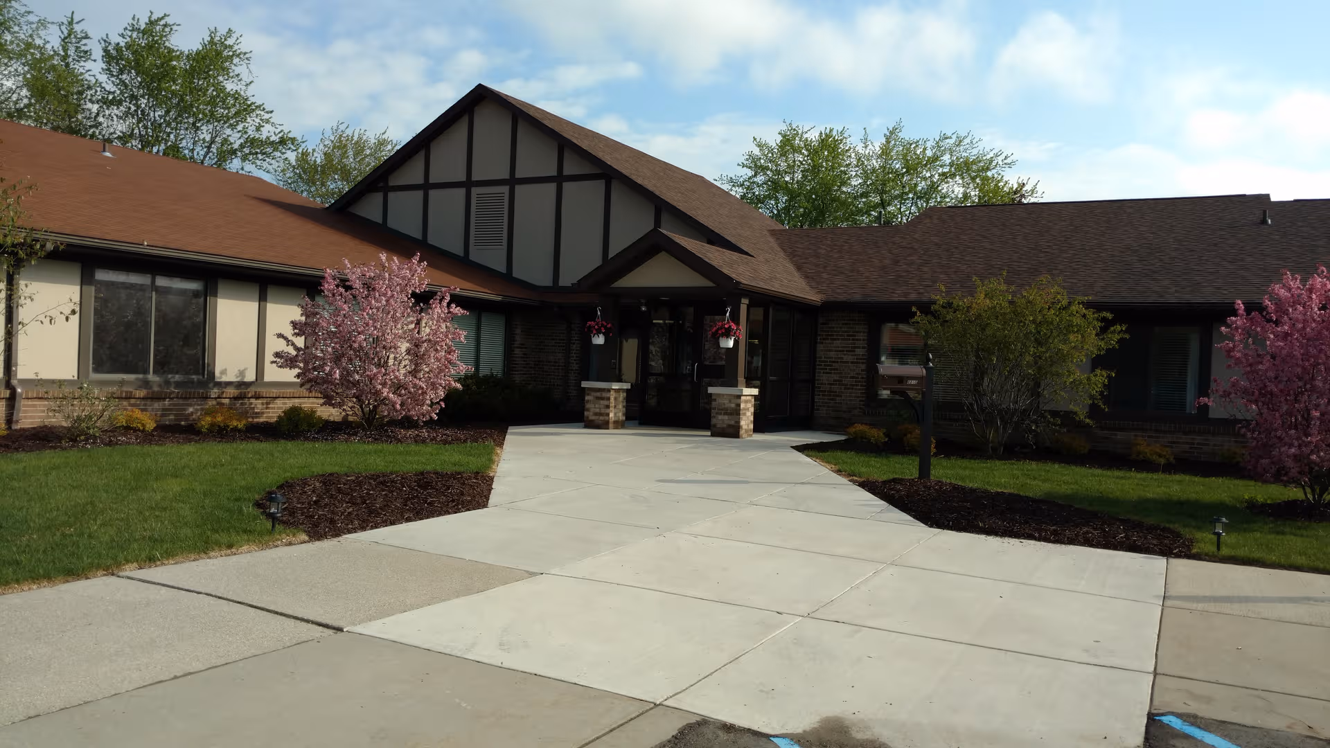 Exterior view of Vibrant Life Senior Living - Durand with a brick building and blooming trees.