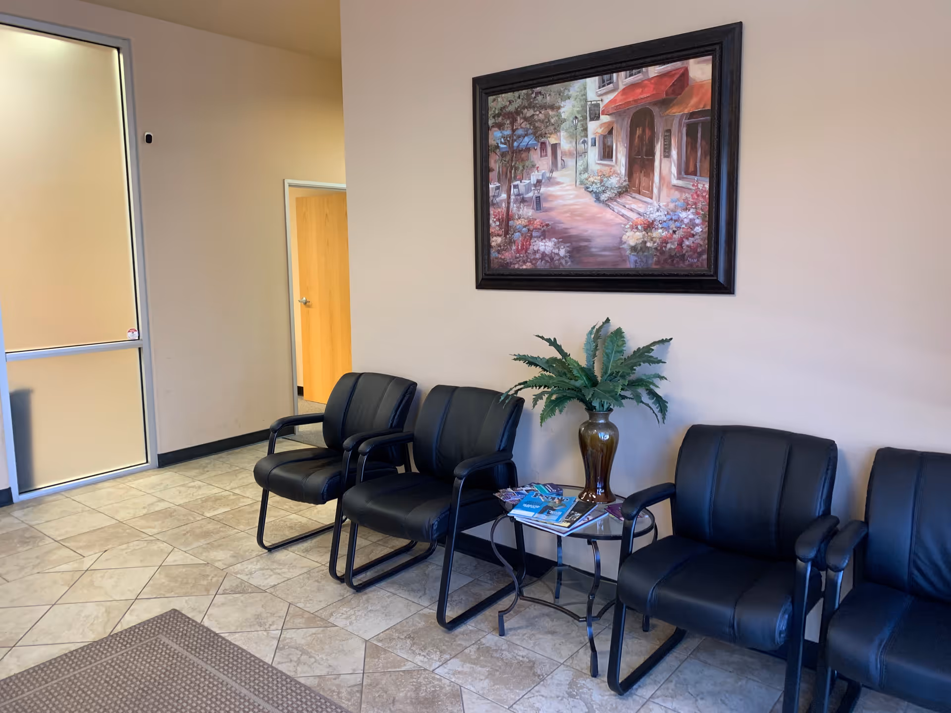 Bakersfield Community Home Health lobby with black leather chairs, plants, magazines, and a framed painting.