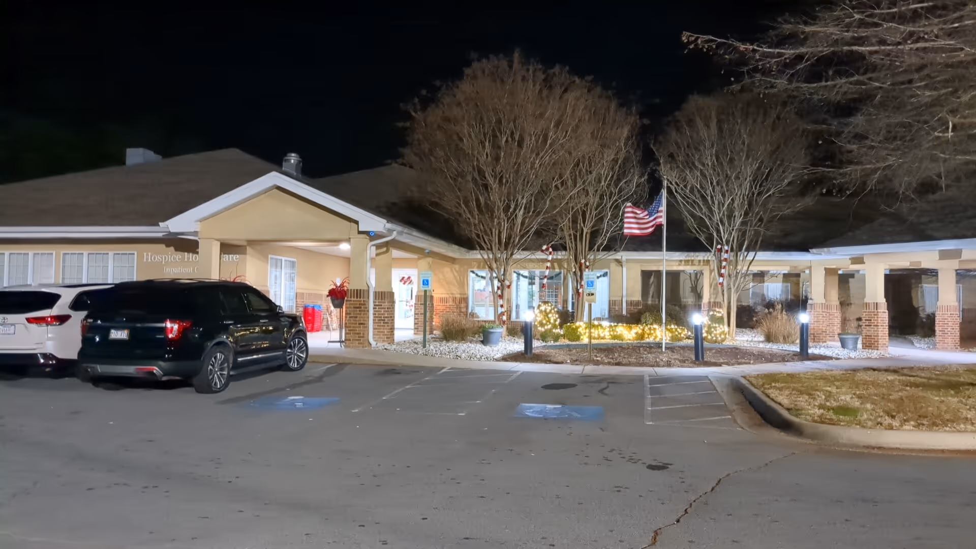 Night view of Hospice and Home Care front entrance with parked cars.