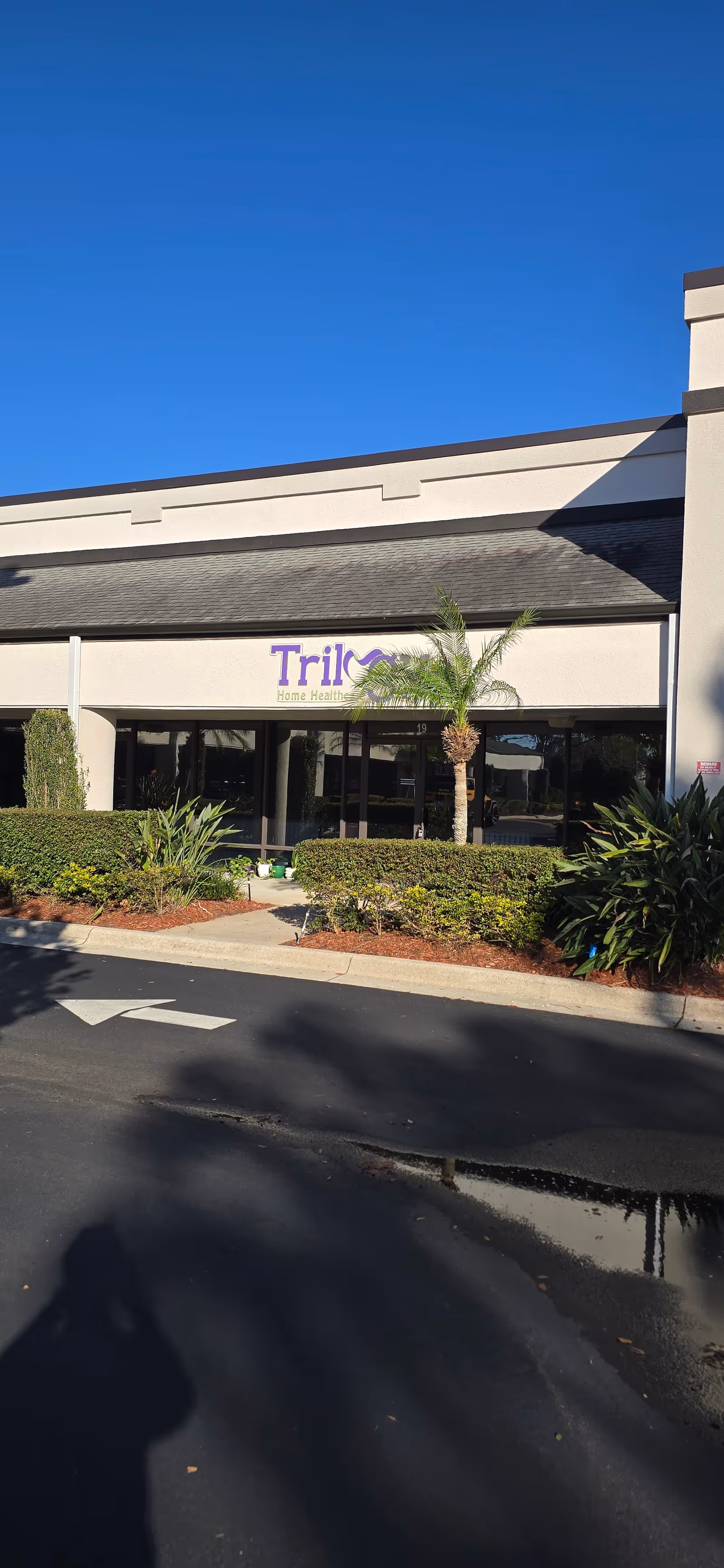 Exterior view of Trilogy Home Healthcare building entrance with landscaping.