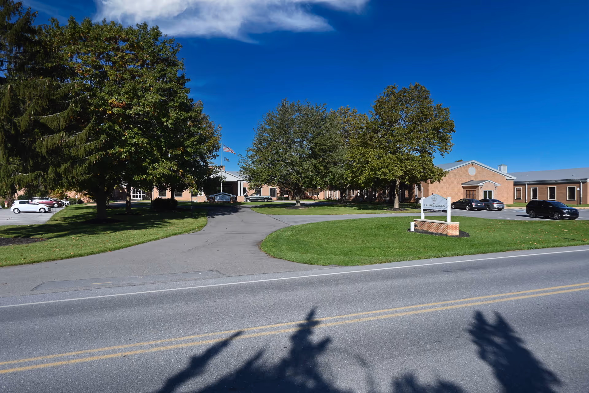 Laurel Lakes Rehabilitation and Wellness Center exterior with driveway, sign, and trees.
