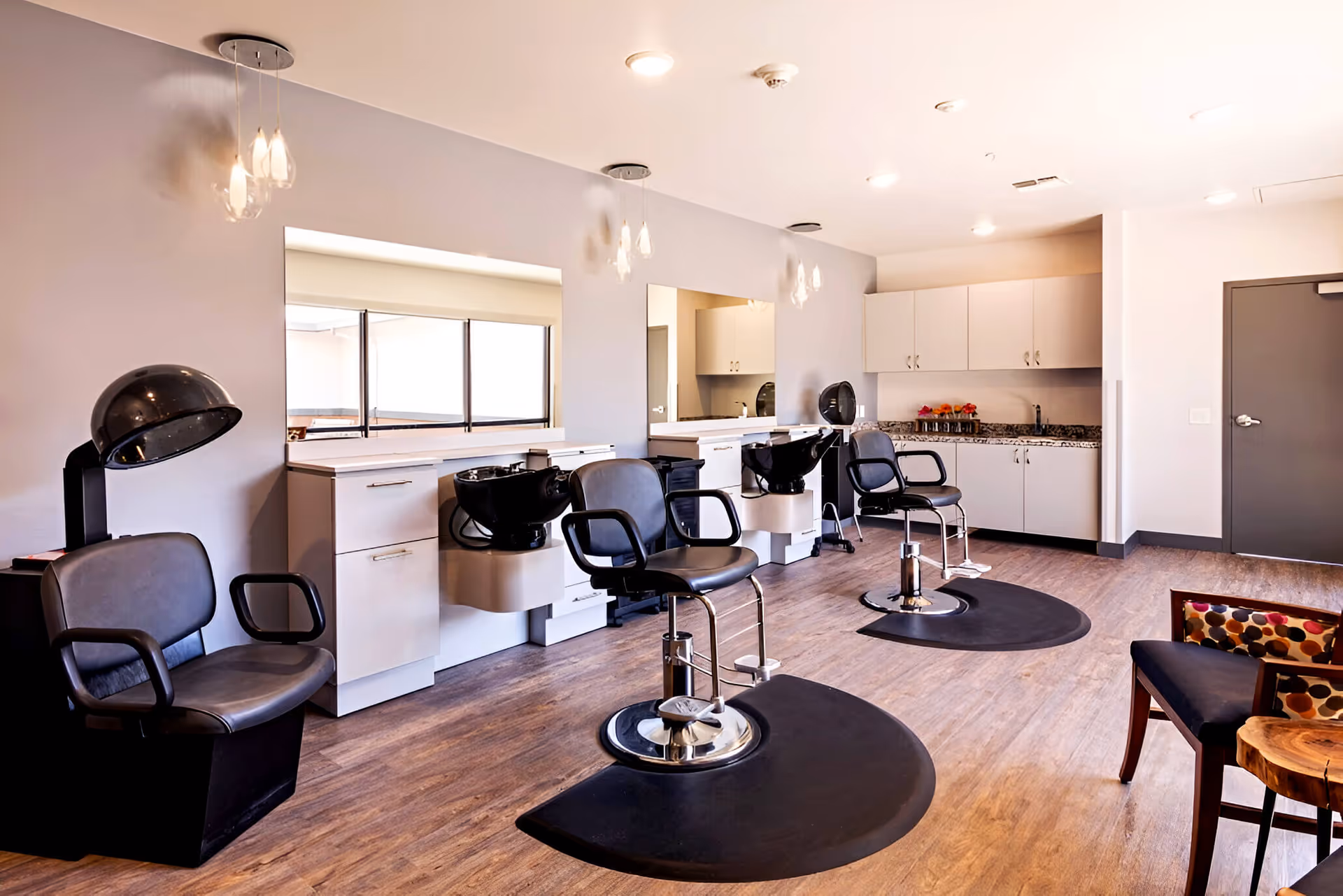 Interior of a modern senior living facility hair salon with chairs, sinks, mirrors.