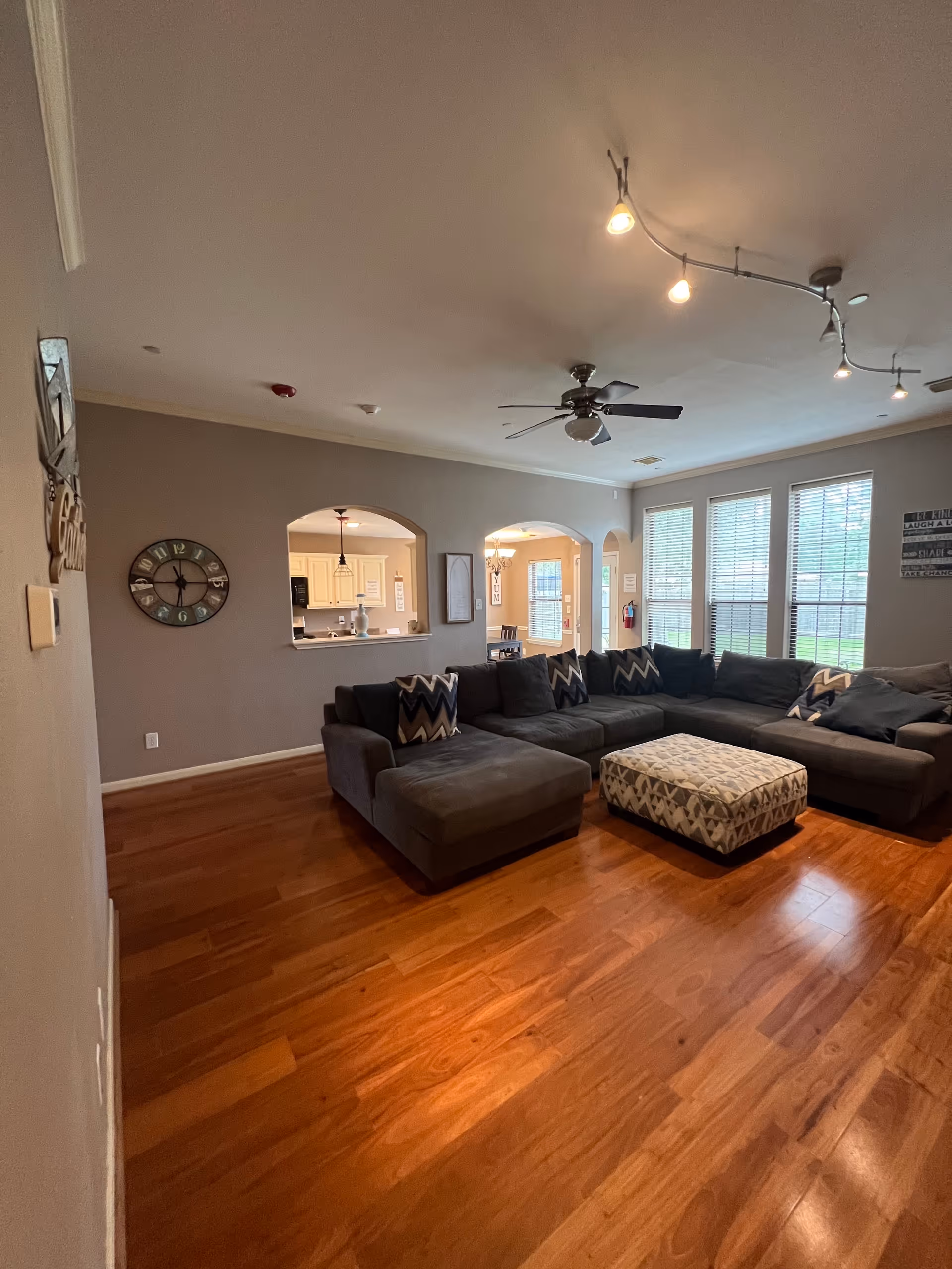 Spacious living room with a large gray sectional, ottoman, and wood floors.