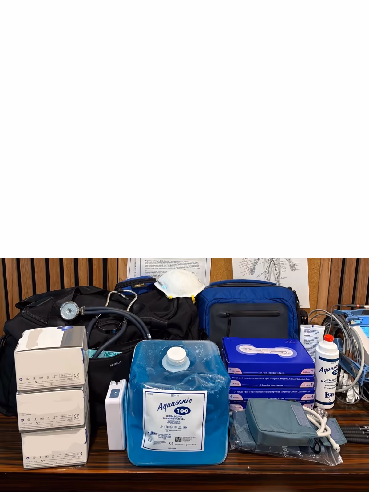 Medical supplies and equipment arranged on a bench, including Aquasonic 100 gel.