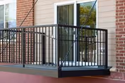 Exterior brick building with a small balcony and black metal railing.