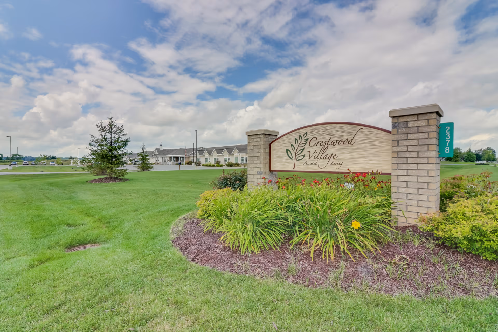 Exterior view of Crestwood Village sign with landscaped entry and green lawn.