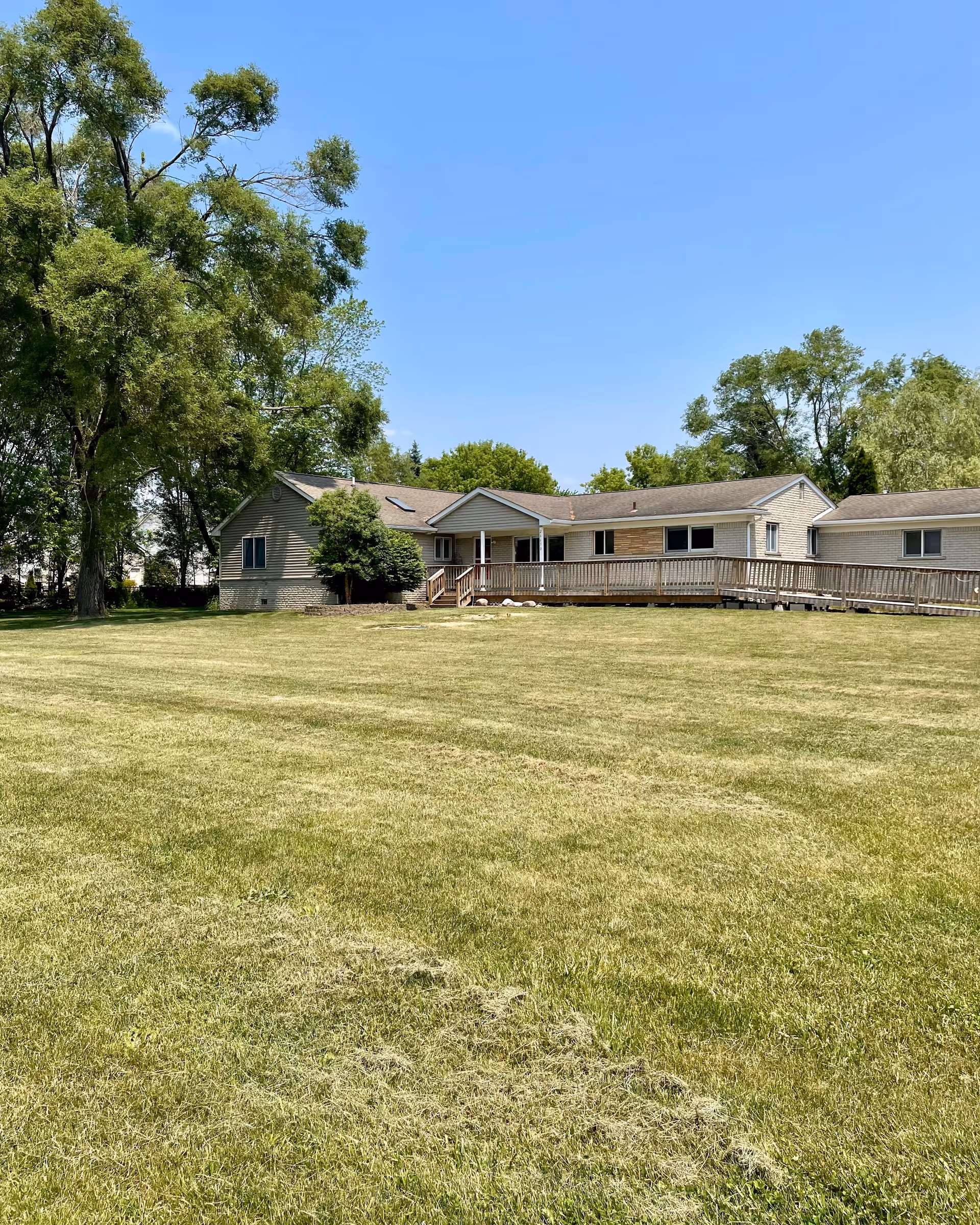 Exterior of Lyon's Trail Senior Living, a single-story facility with a long wooden ramp and lawn.