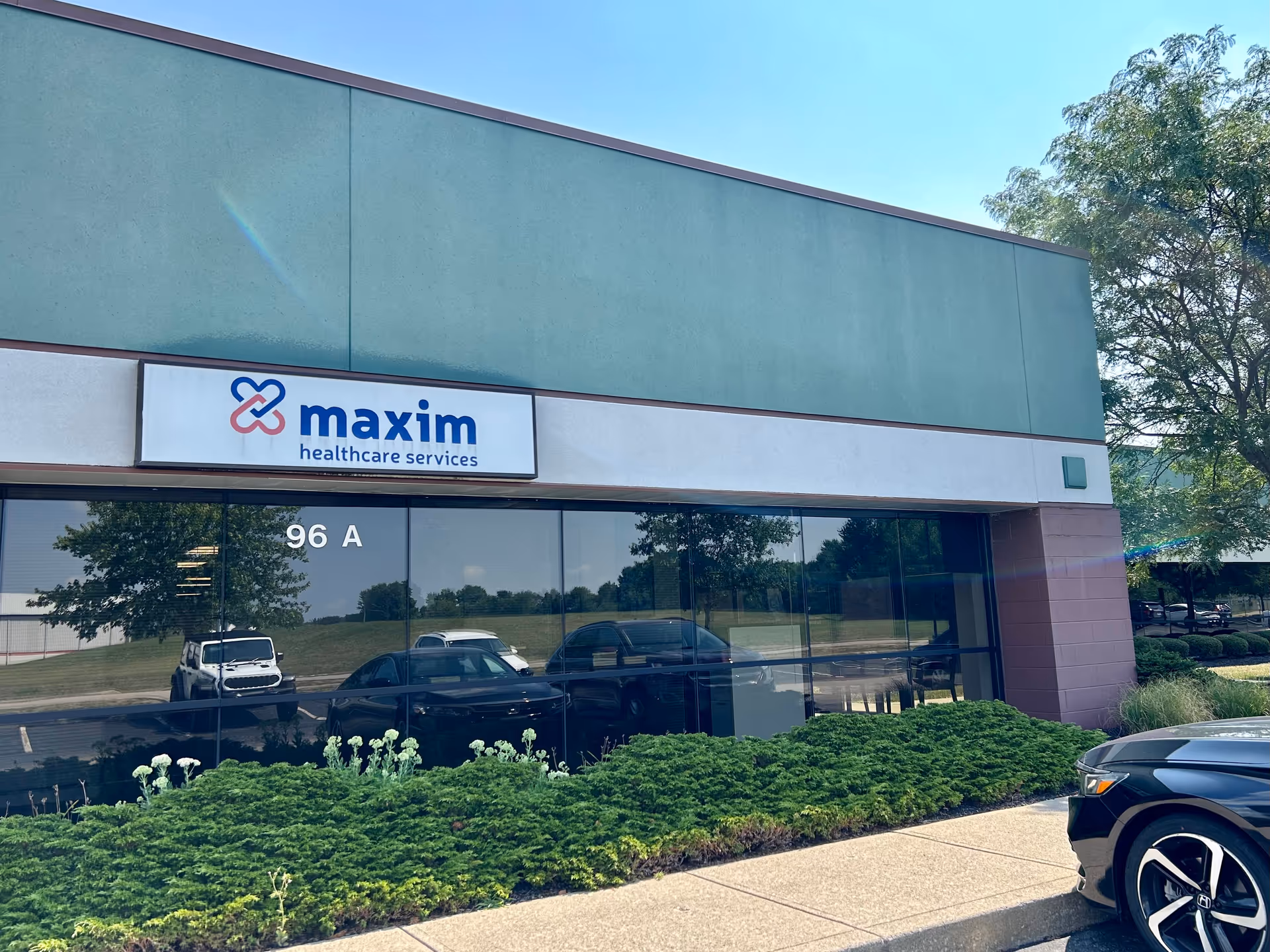 Exterior view of Maxim Healthcare Newark Regional Office with glass storefront and landscaping.
