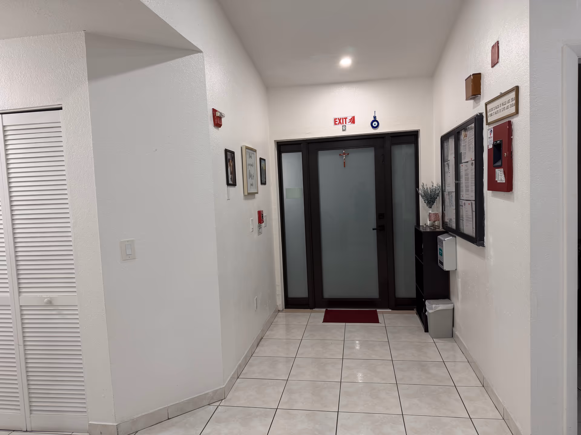 Clean hallway of a senior living facility with frosted glass doors and bulletin boards.