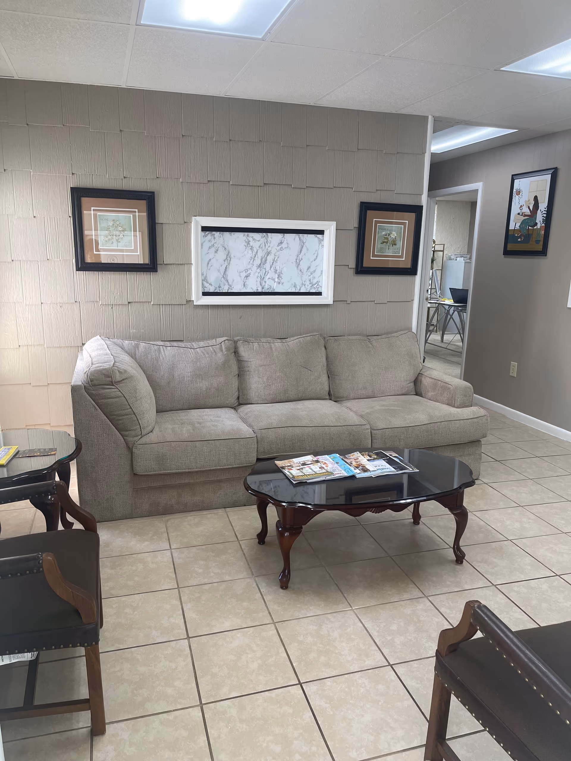 Cozy beige living room with sofa, glass coffee table, and framed wall art.
