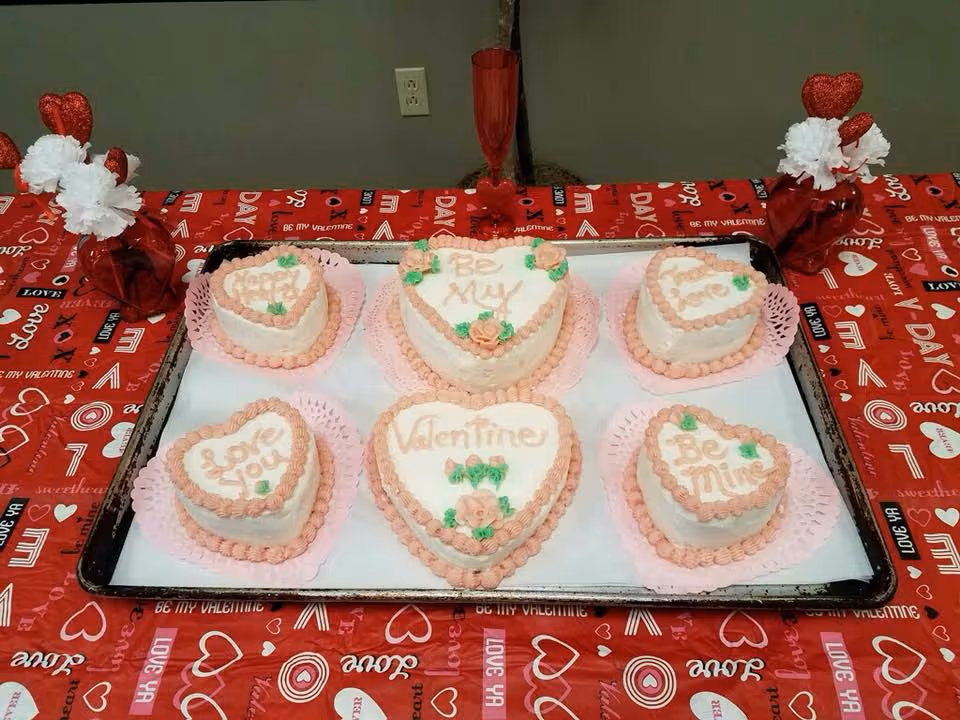 Heart-shaped Valentine's cakes on a tray atop a red love-themed tablecloth.