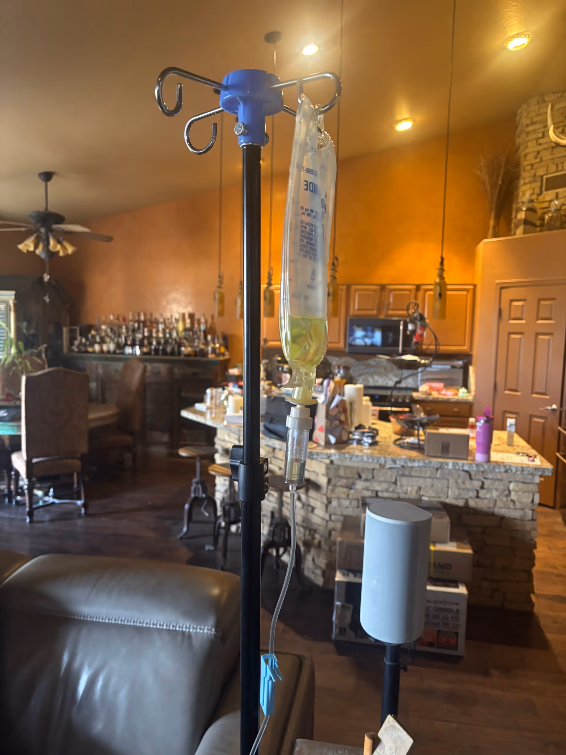 IV drip stand and bag in a cozy living room area with bar background