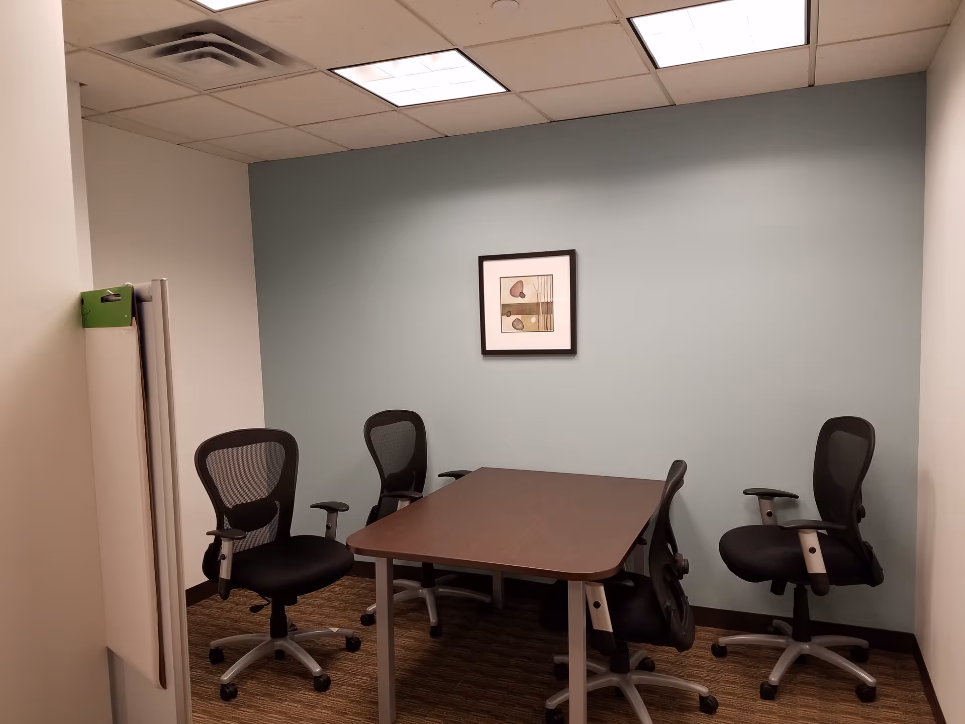 Small conference room with a rectangular table and several black office chairs.