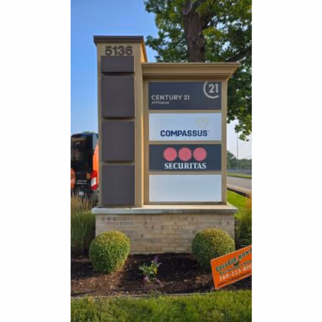 A tall stone sign displays Compassus Home Health and other company logos at a landscaped frontage.
