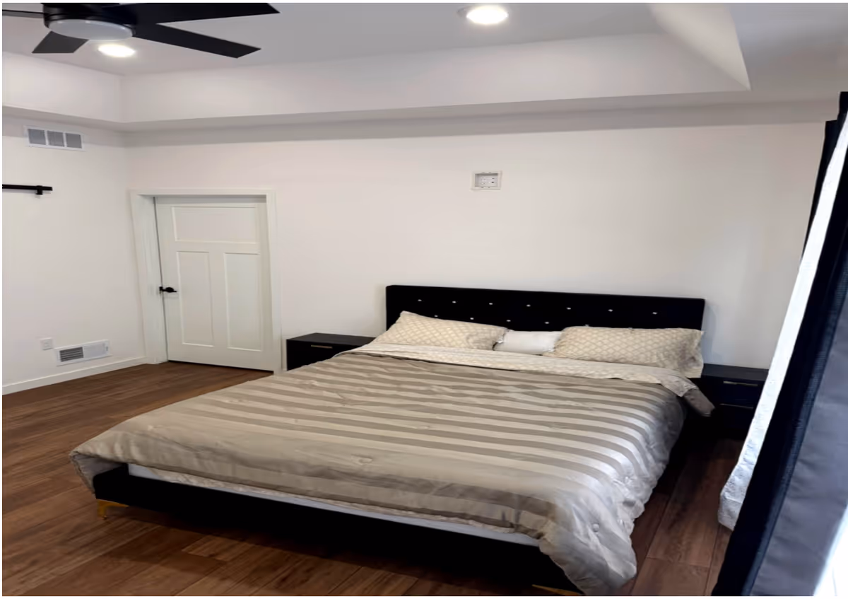 A clean bedroom with a large bed, nightstands, and a ceiling fan.