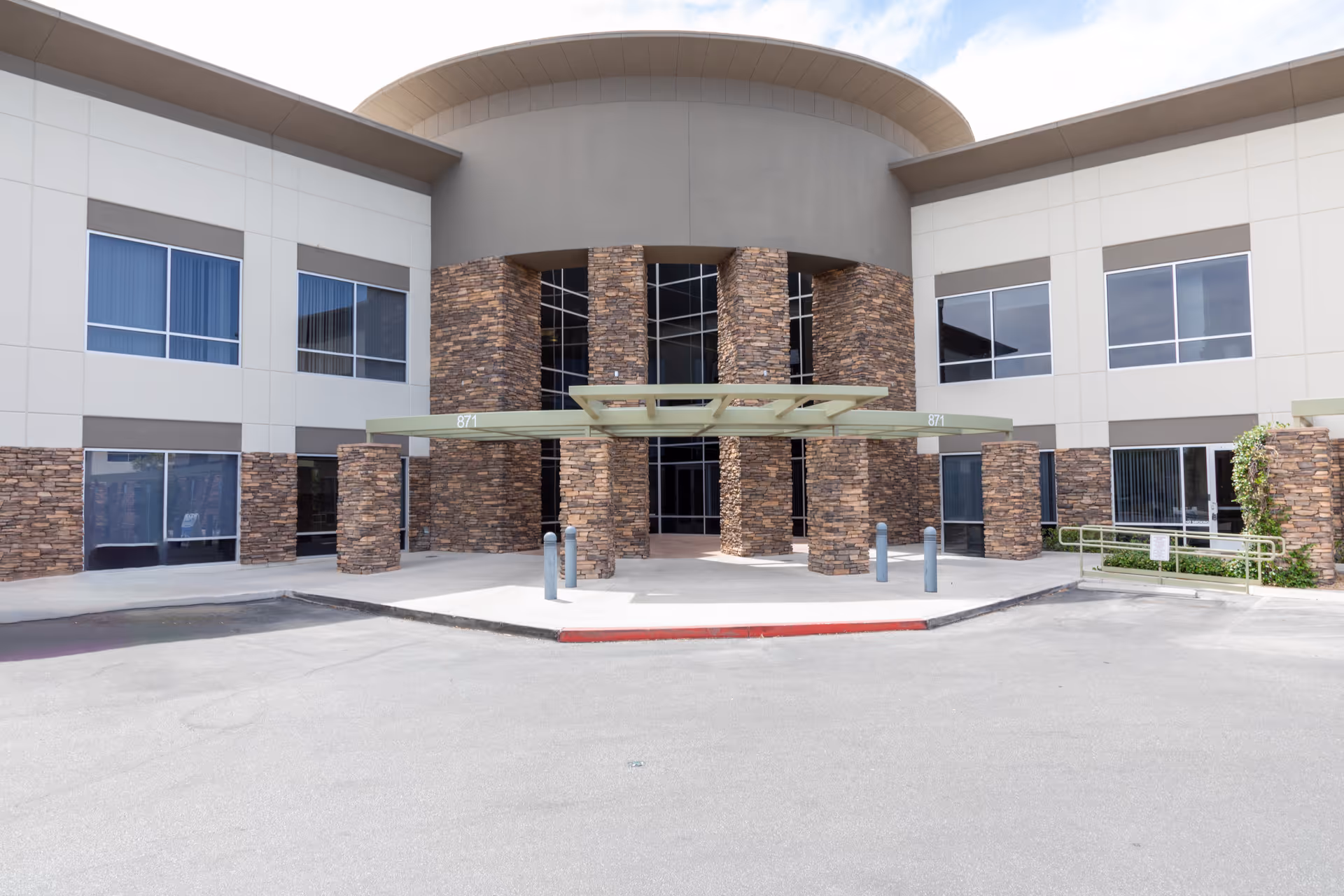 Modern healthcare facility entrance with stone columns and glass doors.